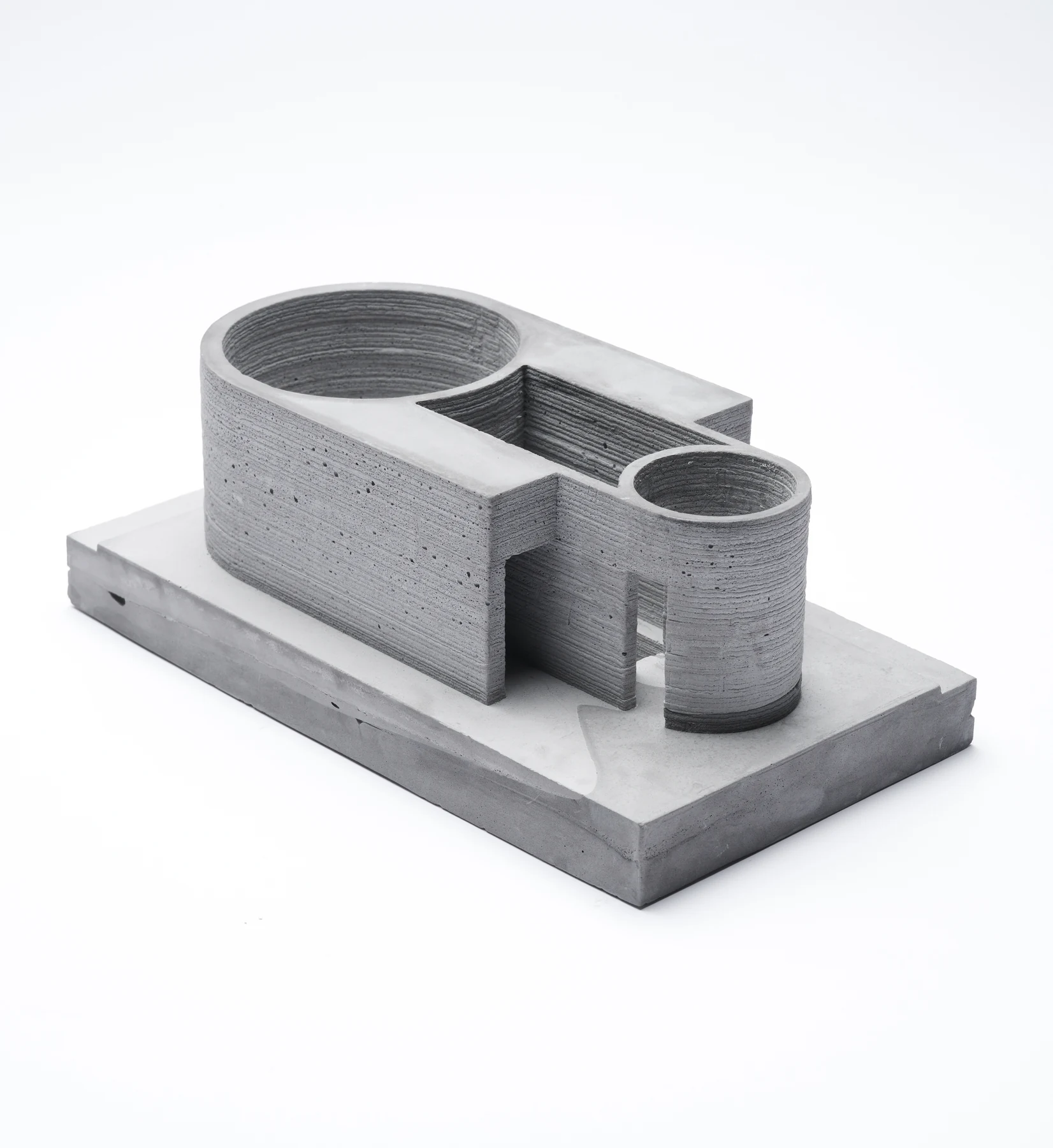 Concrete architectural model of a bathing house with a circular pool and rectangular chambers