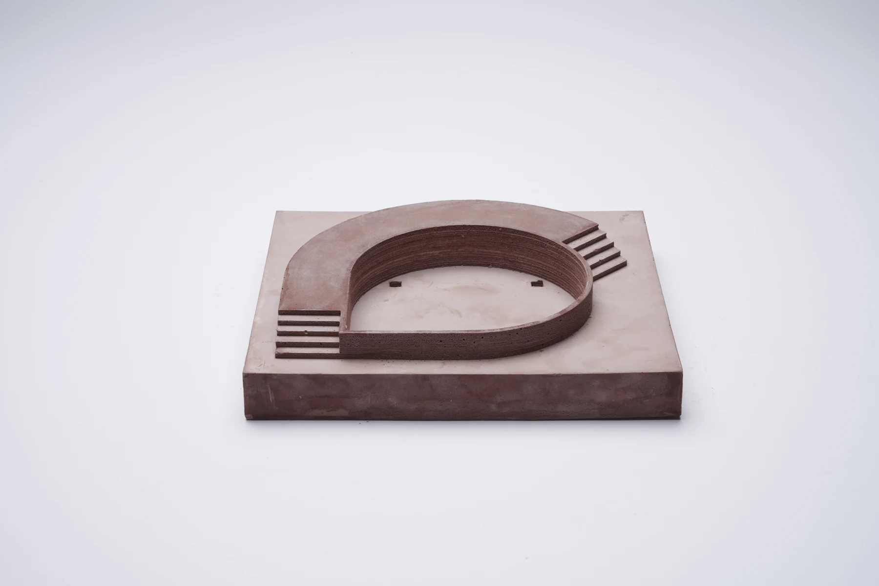 Red plaster model of an oval pool with a stepped edge