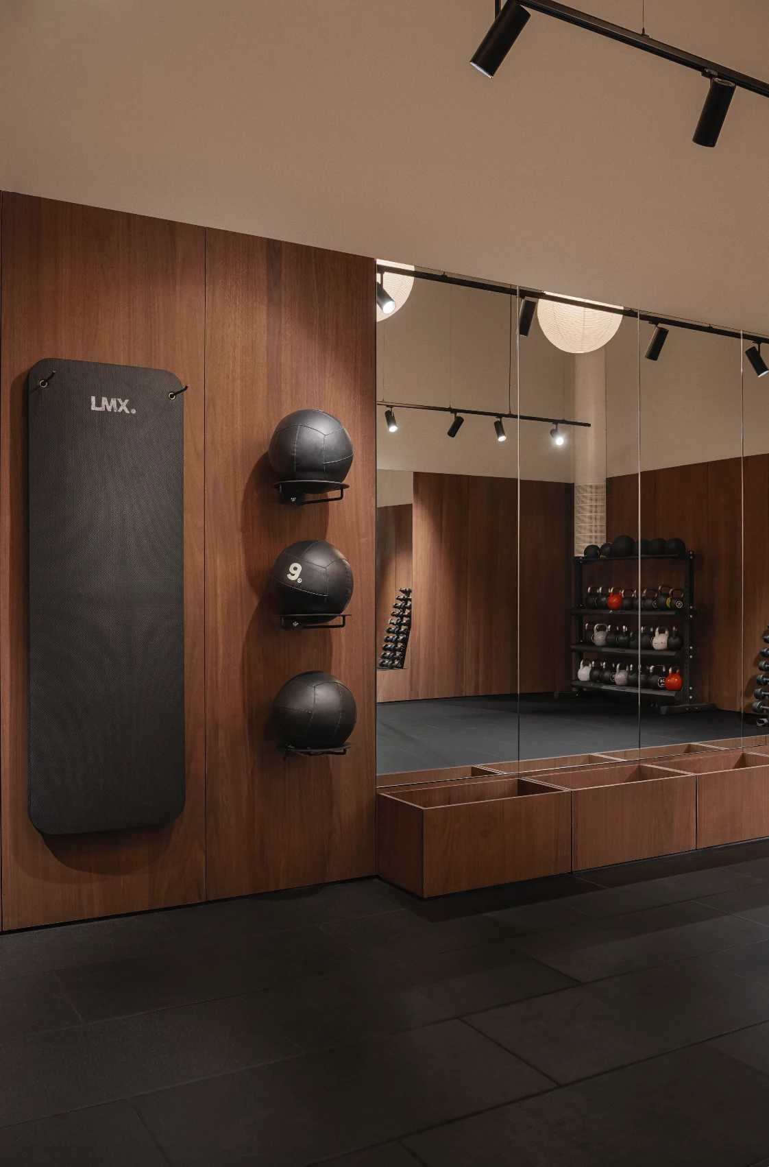 Wall-mounted training pad and medicine balls beside a full-height mirror