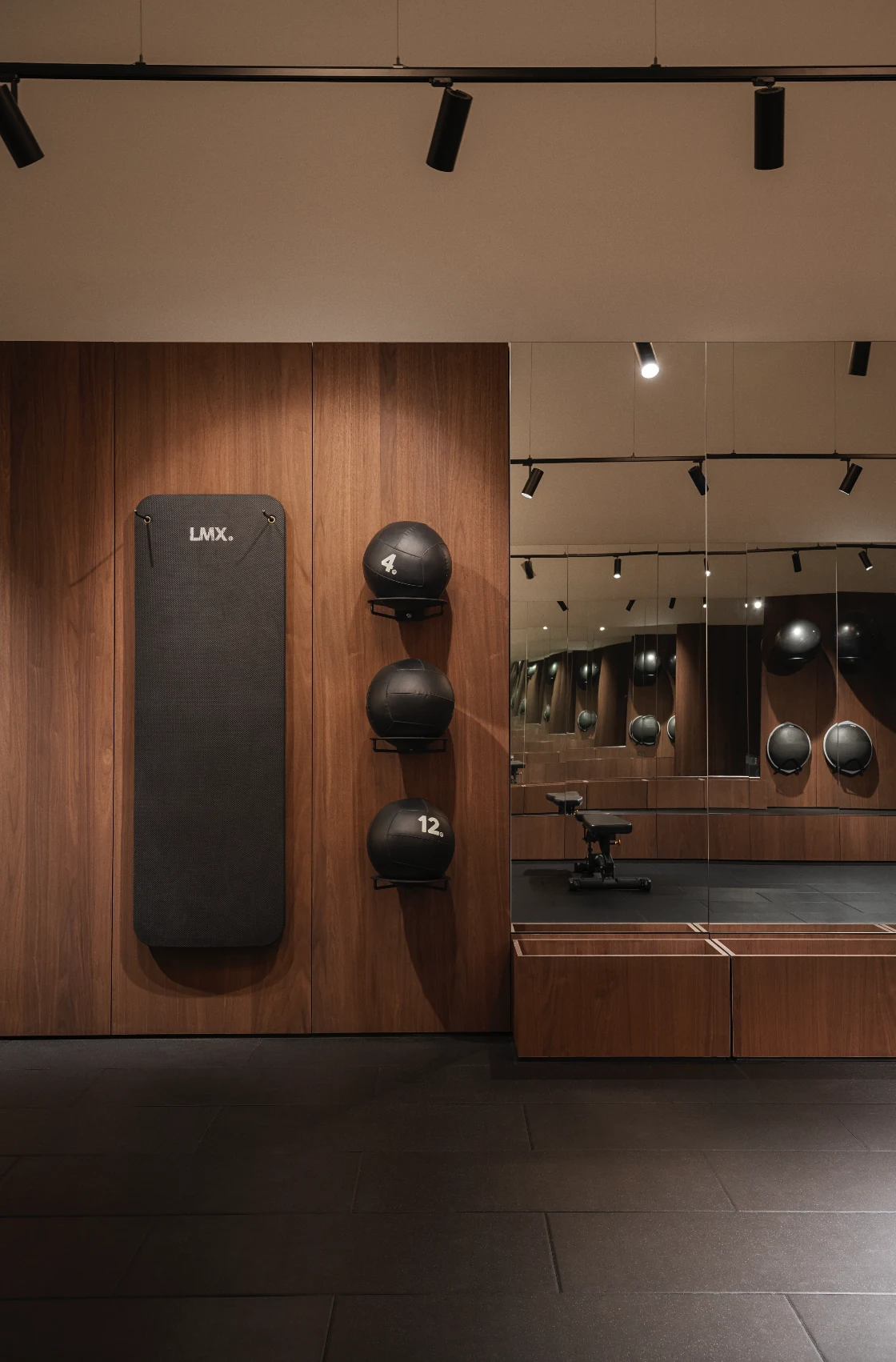 Walnut training wall with mounted pads and weights reflected in the mirror