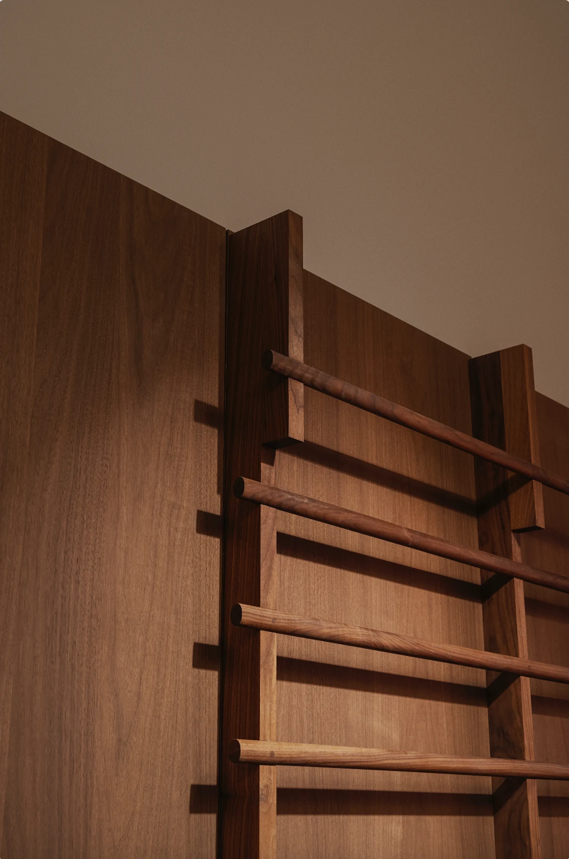 Corner detail where the walnut wall bars meet the panelled wall
