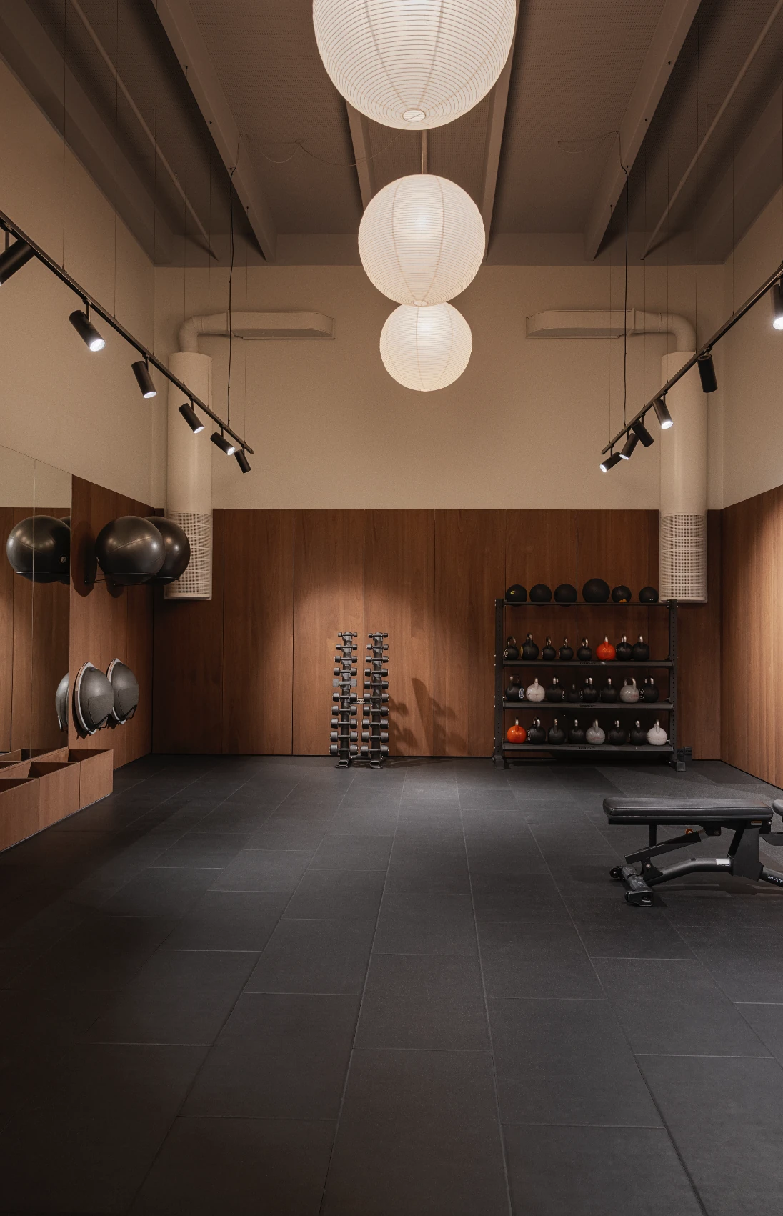 Training room with walnut panelling, paper lantern pendants and free weights