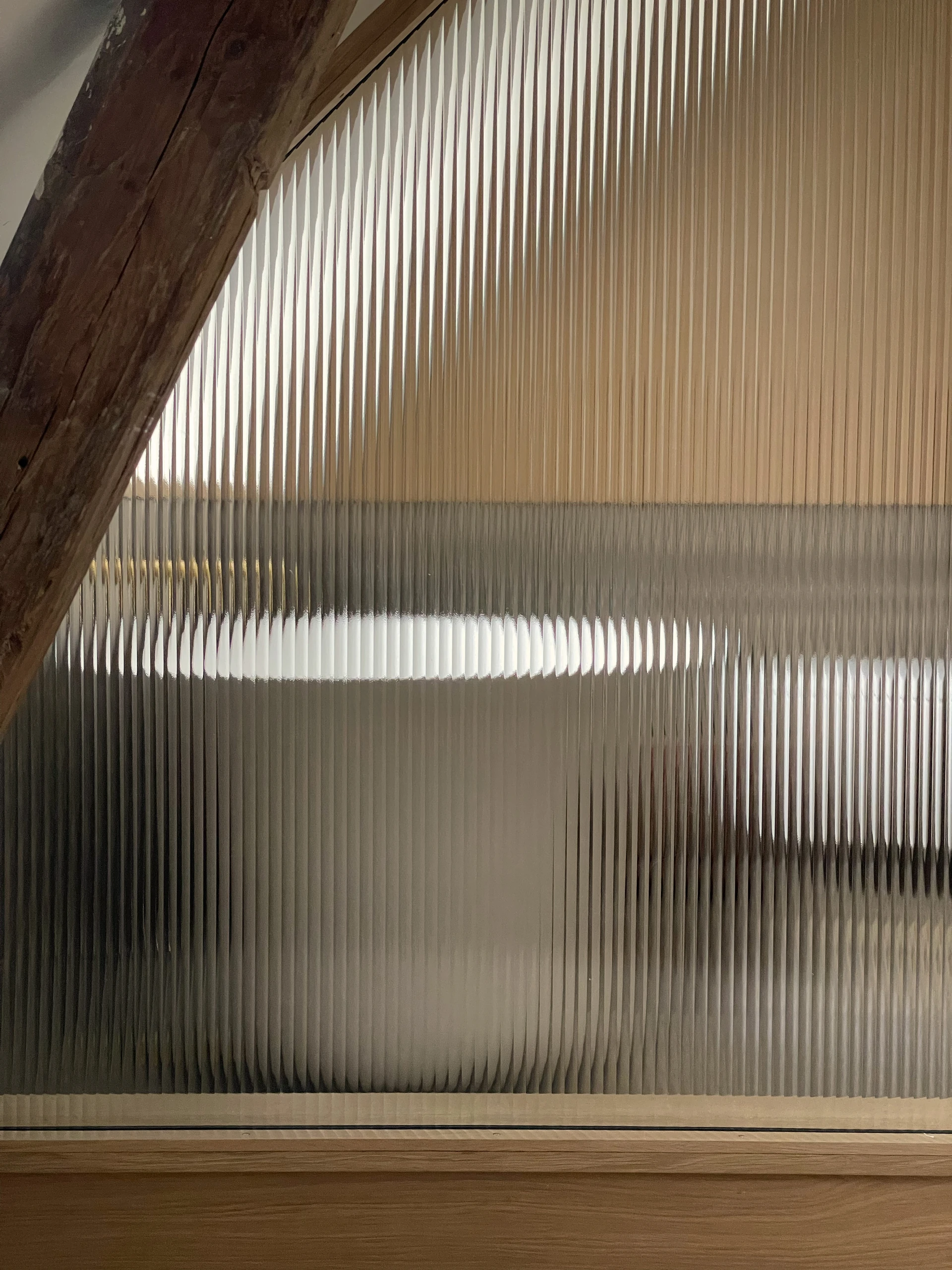 Reeded glass partition beneath an exposed timber roof beam