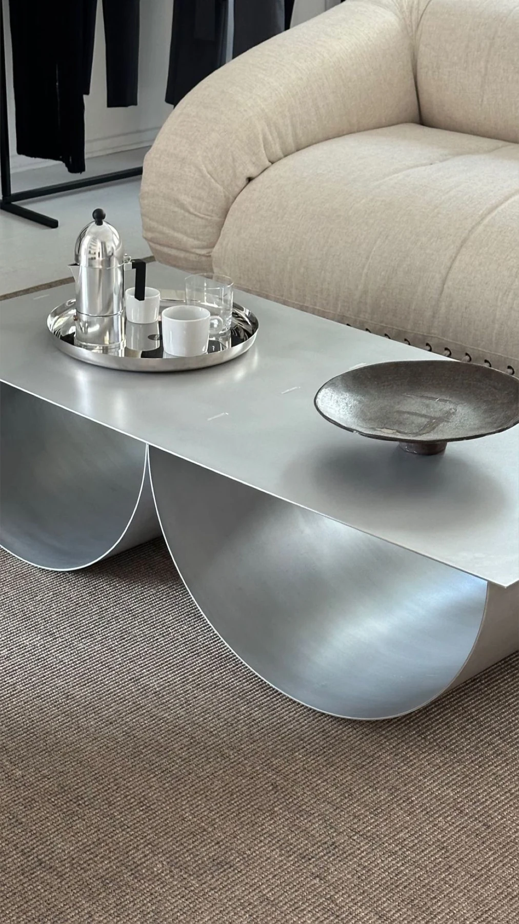 The tabletop and rolled curve of the IB table beside a cream sofa